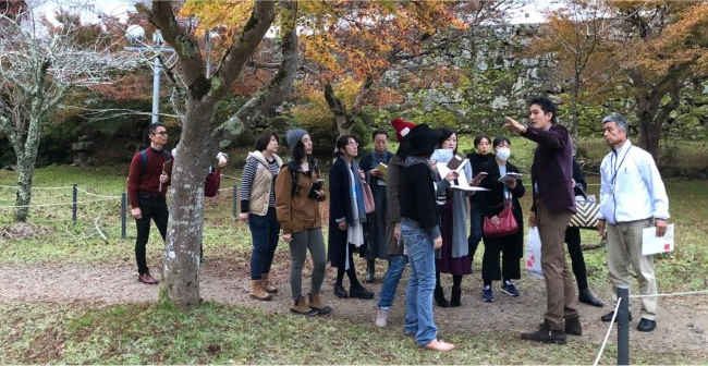 A group of tourists being guided through a Japanese garden in Izushi