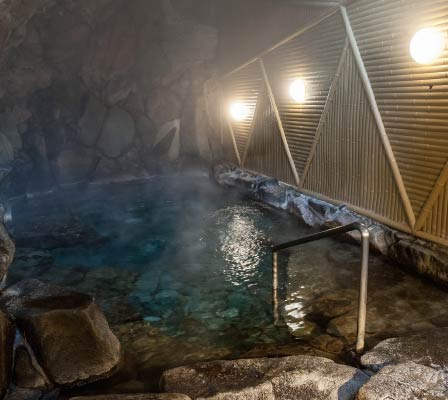 Ichinoyu Onsen's interior bath, surrounded by stones, gives the impression it is in a cave. It is filled with steam