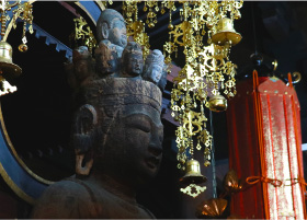 A closeup of a buddhist statue sitting inside the dark and atmoshperic Onsenji Temple