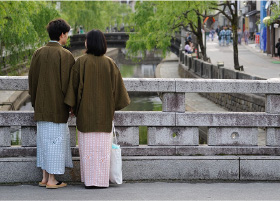 A couple looking over Kinosaki river, standing on a stone bridge