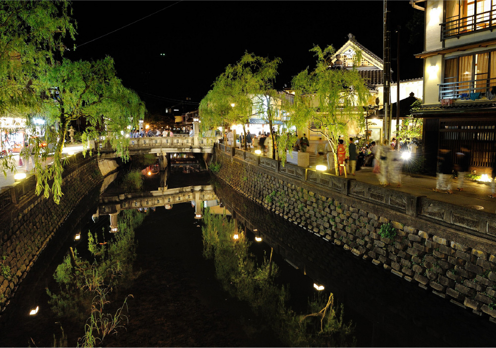 Scenic shot overlooking Kinosaki river. People in colorful Yukata in the background