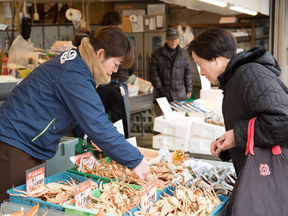 A shop clerk at a fishmarket selling crabs to a local lady