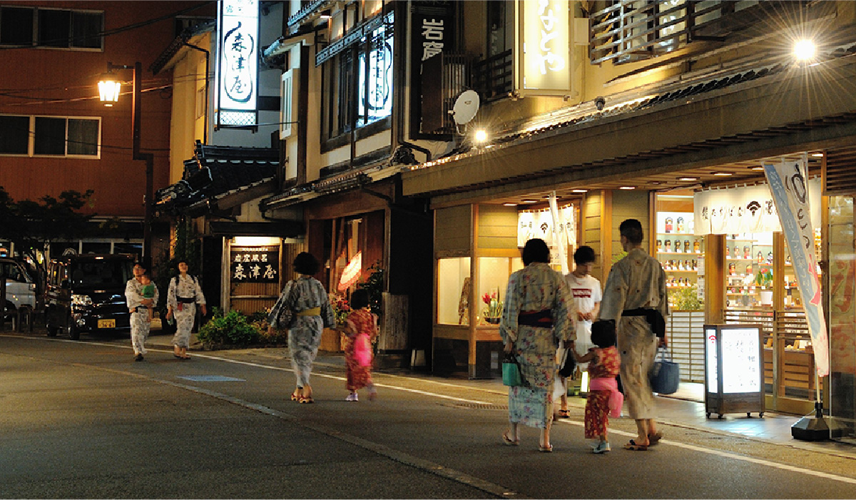 People in colorful Yukata walking the streets of Kinosaki Onsen at night