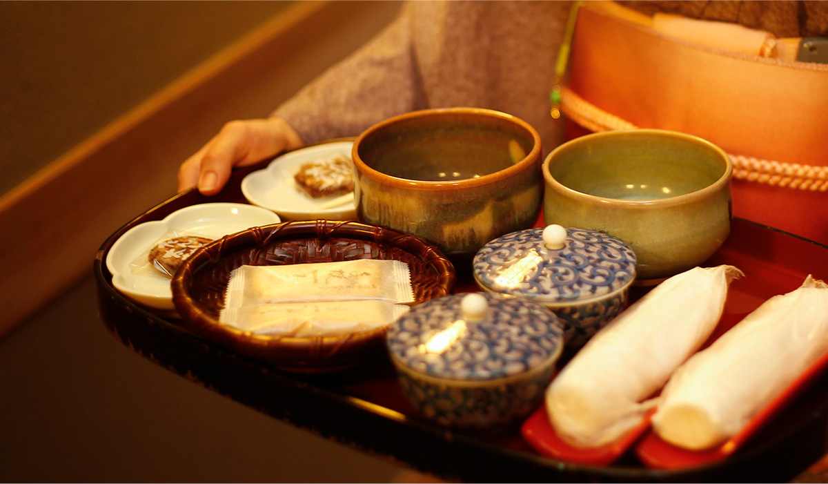 Ryokan staff taking a tray with tea, biscuits and hot napkins to a customer's room