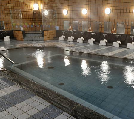 The large interior washroom of Jizoyu Onsen, it has tiled floors and walls and also baths.
