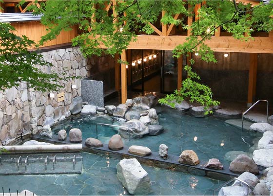 Goshonoyu Onsen's open and expansive outdoor baths. Maple tree branches hang over the pools.